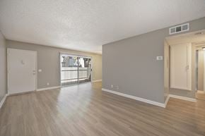 Redlands apartment for rent - Apartment overview of the dining room and living room area with vinyl flooring and gray walls. There is a sliding glass door with blinds to get onto the apartment's patio.