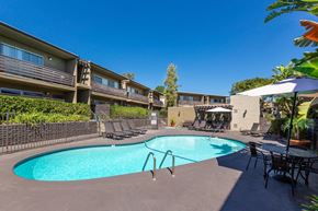 La Mesa apartment for rent - a resort style pool with chairs and umbrellas next to a building