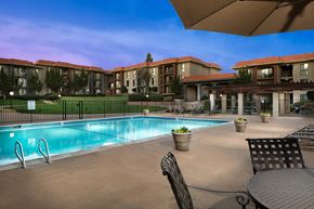 San Diego apartment for rent - A swimming pool surrounded by chairs and tables in front of apartment buildings.