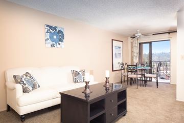 San Diego apartment for rent - A living room with a white couch, a brown table, and a painting on the wall.
