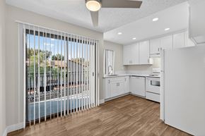 San Diego apartment for rent - A kitchen with white cabinets and a view of a pool through the window.