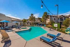 Las Vegas apartment for rent - A pool area with sun loungers and a blue umbrella.