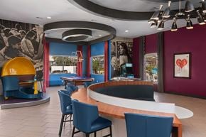 Las Vegas apartment for rent - A modern colorful community room with a curved wooden table surrounded by blue chairs.