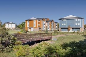 Fort Collins apartment for rent - A bridge crosses a grassy area in front of a row of apartment buildings.