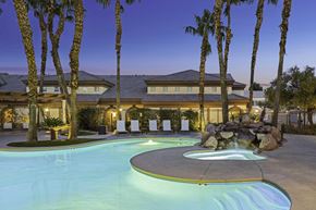 Las Vegas apartment for rent - A pool surrounded by palm trees and a house in the background.