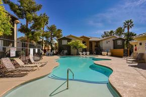 Las Vegas apartment for rent - A swimming pool surrounded by lounge chairs and trees.