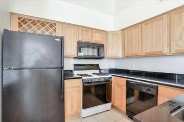 Las Vegas apartment for rent - A black refrigerator is in a kitchen with wooden cabinets.