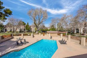 Las Vegas apartment for rent - A large swimming pool surrounded by a concrete patio and lounge chairs.