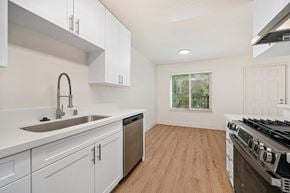 Modesto apartment for rent - The kitchen of the renovated apartments with stainless steel appliances, wood style plank flooring, white cabinets, and faux marble countertops.