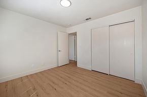 Modesto apartment for rent - The bedroom of the renovated apartments with wood style plank flooring, white walls, and a closet.