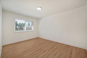 Modesto apartment for rent - The bedroom of the renovated apartments with wood style plank flooring, white walls, and a window.