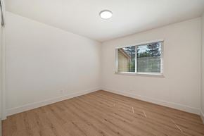 Modesto apartment for rent - The bedroom of the renovated apartments with wood style plank flooring, white walls, and a window.