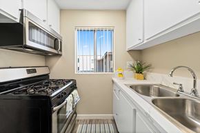 Sherman Oaks apartment for rent - Kitchen area with stainless front appliances, quartz countertops, white countertops, and a small window with blinds.