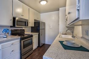 Sherman Oaks apartment for rent - A kitchen with white cabinets, Formica counters, stainless front appliances, and hardwood style vinyl flooring.