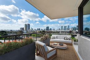 San Diego apartment for rent - A balcony with a couch, chair, and table overlooking a city skyline.