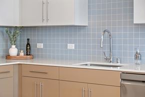 San Diego apartment for rent - A kitchen with a blue tile backsplash, white counters, and a stainless steel sink.