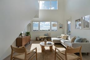 San Diego apartment for rent - A living room with a couch, chairs, and a table. The ceiling is high with two rows of windows.