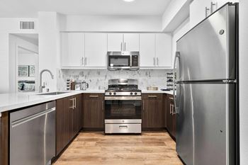 Fully equipped kitchens with stainless steel appliances, including refrigerator, stove, dishwasher, microwave, and garbage disposal