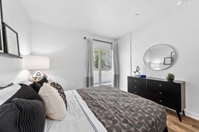 Los Angeles apartment for rent - A bedroom with a large bed, a dresser, and a round mirror on the wall.