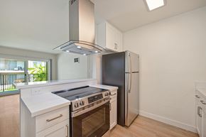 Oceanside apartment for rent - A kitchen with stainless steel appliances, white countertops, and white cabinets.