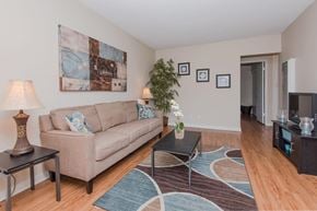 Ventura apartment for rent - A living room with wood style flooring and beige walls. The room is staged with a couch, coffee table, a rug, and a lamp.