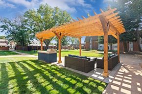 Greeley apartment for rent - A wooden pergola is over bench seating in a grassy area.