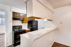 Greeley apartment for rent - A kitchen with a black stove top oven, breakfast bar, and a black refrigerator.