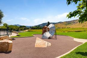 Boulder apartment for rent - A playground with a white curved climbing wall and a brown rock in a green space.