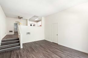 Sherman Oaks apartment for rent - A living room with white walls, vinyl wood flooring, and a few stairs to get to the dining room and kitchen area.