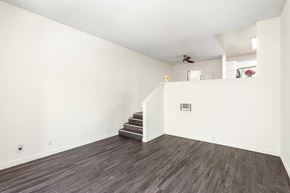 Sherman Oaks apartment for rent - A living room with white walls, vinyl wood flooring, and a few stairs to get to the dining room and kitchen area.