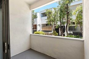 Sherman Oaks apartment for rent - A balcony with a view of a building and trees.