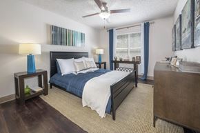 Tampa apartment for rent - A bedroom with a bed, nightstand, and a ceiling fan.