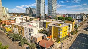 San Diego apartment for rent - 900 F Street against a cityscape with buildings in the foreground and a clear blue sky above.
