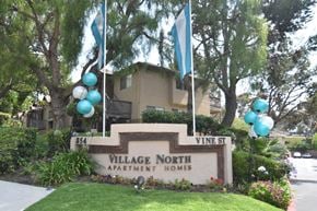 Oceanside apartment for rent - a photo of the village north apartment homes sign with blue and white balloons above it