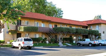 Vista apartment for rent - a yellow apartment building with cars parked in front of it