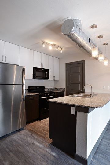 Denton apartment for rent - A modern kitchen with a stainless steel refrigerator and a microwave above the stove.