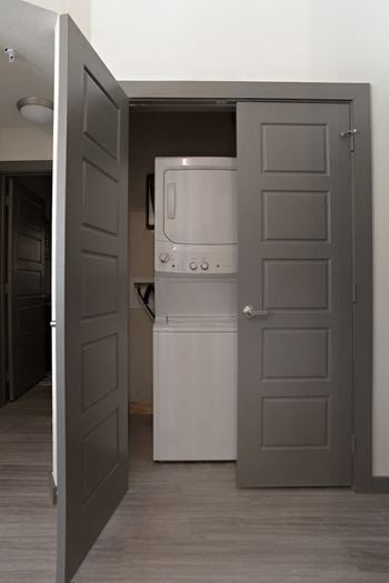 An open door to a kitchen with a refrigerator and a washing machine