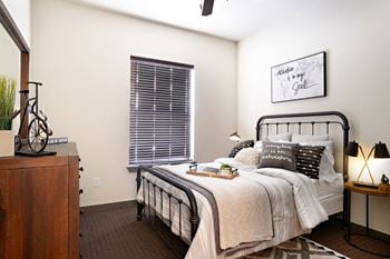 A bedroom with a bed and a dresser and a window