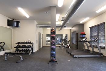 A gym with weights and other exercise equipment and a television