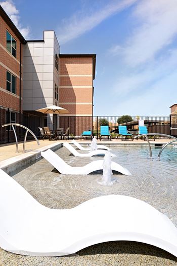 A swimming pool with a fountain in front of a building