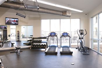 A gym with treadmills and other exercise equipment and a large window