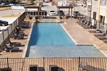 A swimming pool on the rooftop of a hotel with lounge chairs