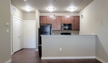 Denton apartment for rent - A kitchen with a black refrigerator and brown cabinets.