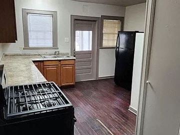 Denton apartment for rent - A kitchen with a black fridge and a black stove top.