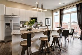 Columbus apartment for rent - A modern kitchen with a granite countertop and bar stools. at 985 High Apartments, Columbus, OH, 43201