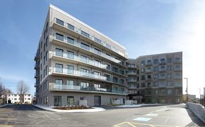 Kingston apartment for rent - a view of the building from a parking lot with a blue sky