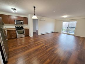 Kingston apartment for rent - an empty kitchen and living room with wood flooring in an empty house