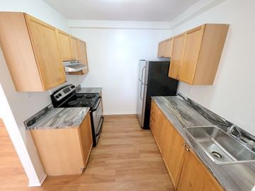 Kingston apartment for rent - A kitchen with wooden cabinets and a black fridge.