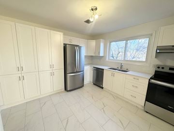Kingston apartment for rent - A kitchen with white cabinets and a stainless steel refrigerator.