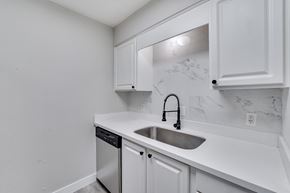 Houston apartment for rent - A kitchen with white cabinets and a marble backsplash.